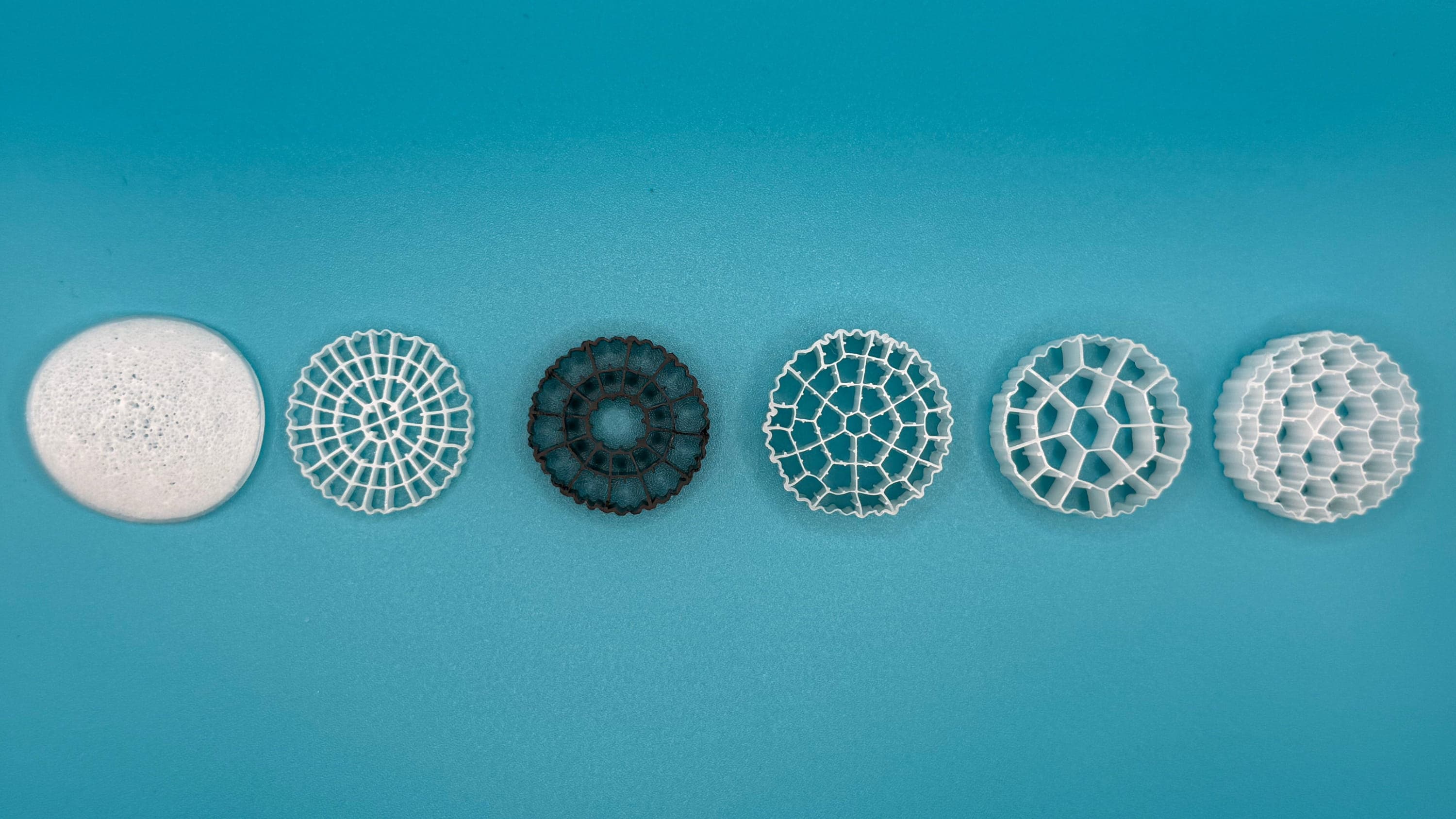 Six types of MBBR media carriers laid out on a blue surface